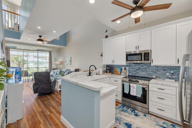 kitchen featuring appliances with stainless steel finishes, sink, white cabinetry, kitchen peninsula, and decorative backsplash