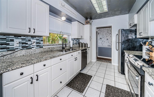 kitchen featuring stone countertops, stainless steel appliances, sink, and white cabinets