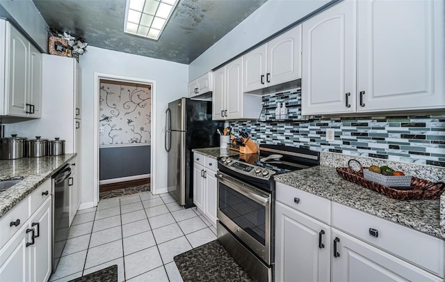 kitchen with white cabinetry, stainless steel appliances, and dark stone counters