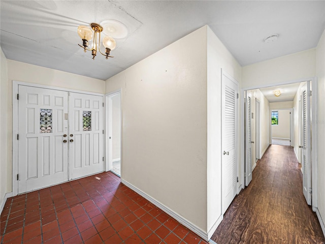 entryway featuring dark wood-type flooring and a chandelier