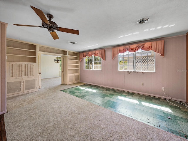 empty room with carpet, ceiling fan, and built in features