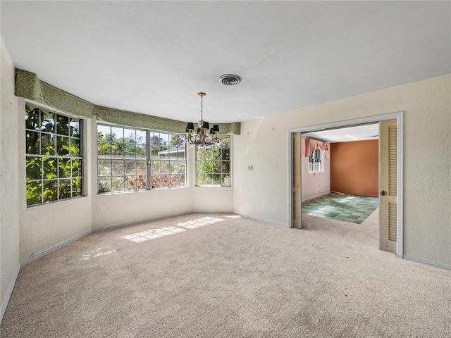 empty room with light carpet and a chandelier