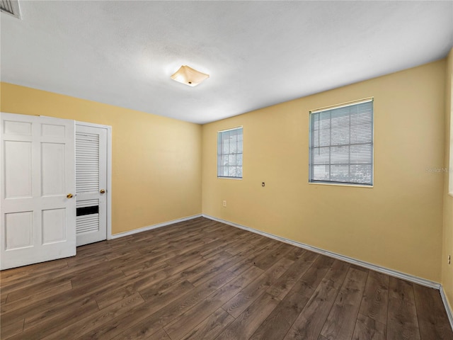 unfurnished bedroom with a closet and dark wood-type flooring