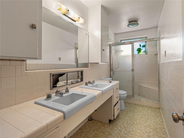 bathroom featuring a shower with shower door, tile walls, and toilet