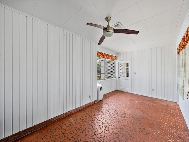 spare room with wood walls and ceiling fan