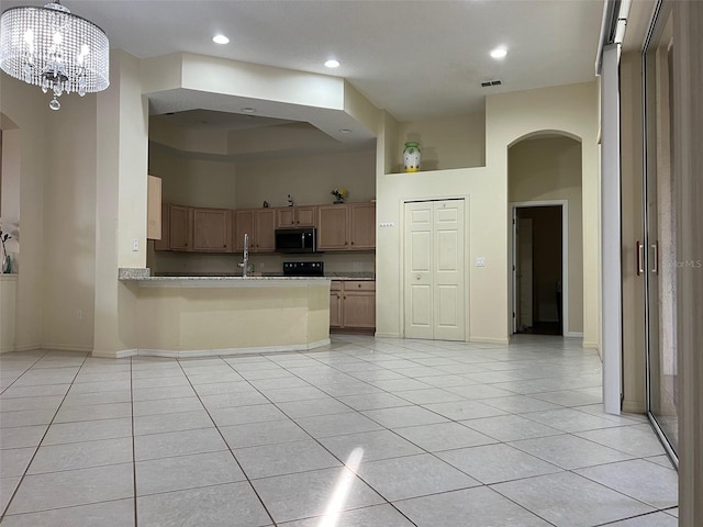 kitchen with black appliances, kitchen peninsula, a towering ceiling, and light tile patterned floors