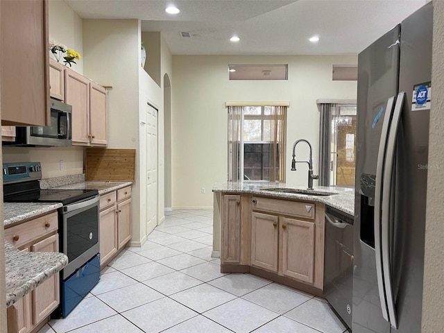 kitchen with light stone counters, light tile patterned floors, light brown cabinetry, sink, and stainless steel appliances