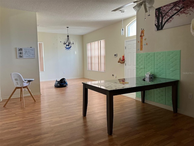 recreation room featuring a textured ceiling, ceiling fan with notable chandelier, and hardwood / wood-style floors