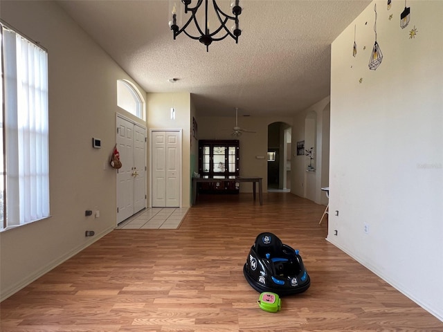 entryway with light hardwood / wood-style floors, a textured ceiling, and ceiling fan with notable chandelier