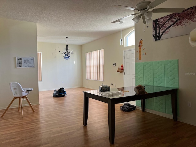 rec room with wood-type flooring, a textured ceiling, and ceiling fan with notable chandelier