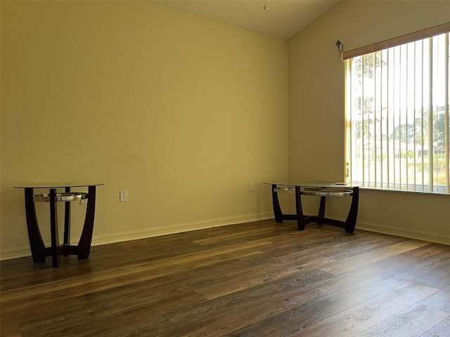 unfurnished room with lofted ceiling, dark hardwood / wood-style floors, and a textured ceiling