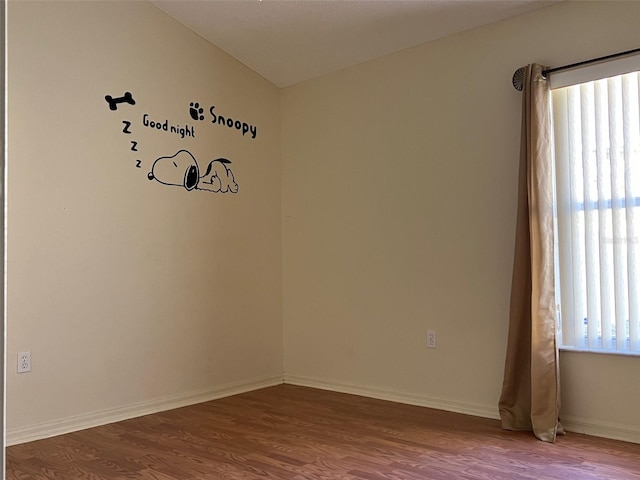 spare room featuring lofted ceiling, wood-type flooring, and a healthy amount of sunlight