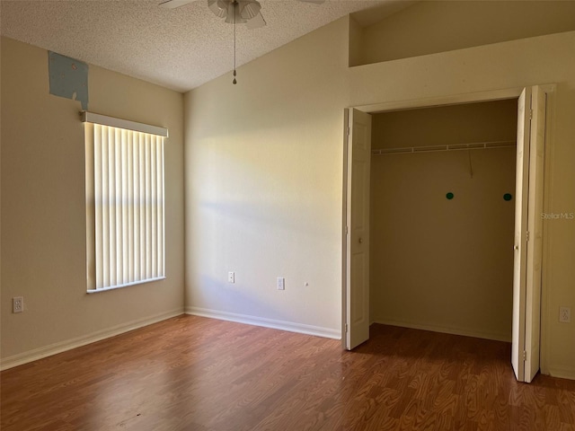 unfurnished bedroom with ceiling fan, a textured ceiling, wood-type flooring, vaulted ceiling, and a closet