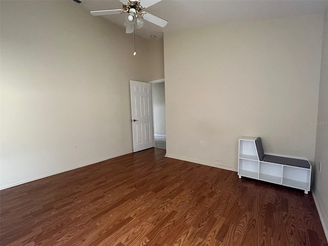 spare room featuring ceiling fan, a towering ceiling, and dark hardwood / wood-style flooring