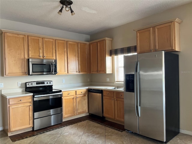 kitchen with light tile patterned flooring, a textured ceiling, and appliances with stainless steel finishes