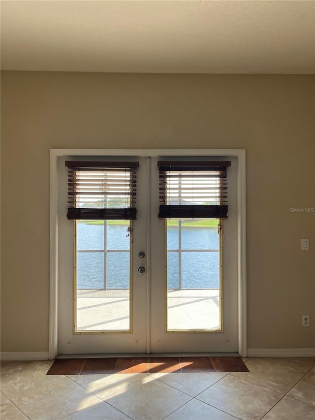 doorway featuring light tile patterned floors, a water view, and french doors