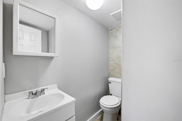 bathroom with vanity, toilet, and a textured ceiling