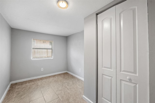 interior space featuring a closet, a textured ceiling, and light tile patterned flooring