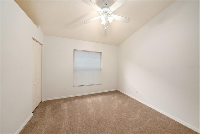 carpeted empty room with ceiling fan and lofted ceiling