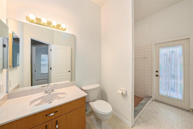 bathroom with vanity, toilet, and a tile shower