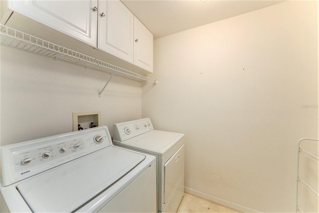 laundry area featuring washing machine and dryer, cabinets, and a textured ceiling