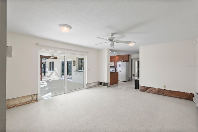 unfurnished living room with ceiling fan and a textured ceiling