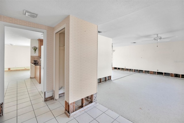 hall with a textured ceiling and light tile patterned floors