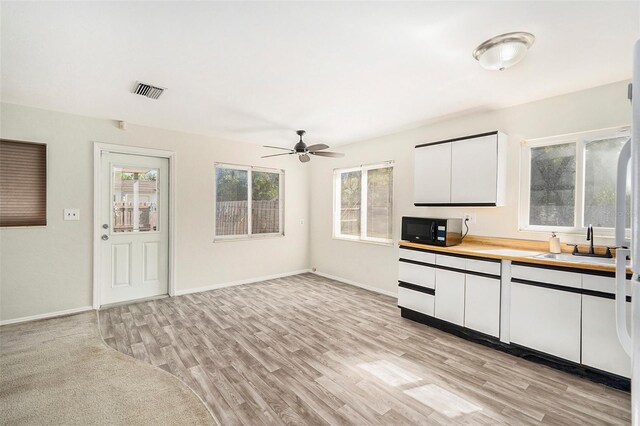 kitchen featuring white cabinetry, ceiling fan, sink, and light hardwood / wood-style flooring