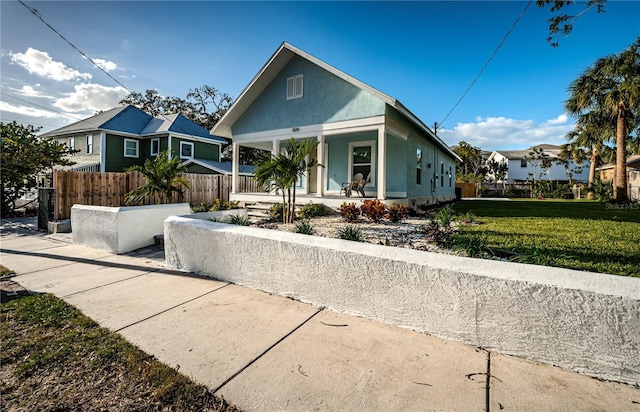 bungalow-style home with covered porch and a front yard