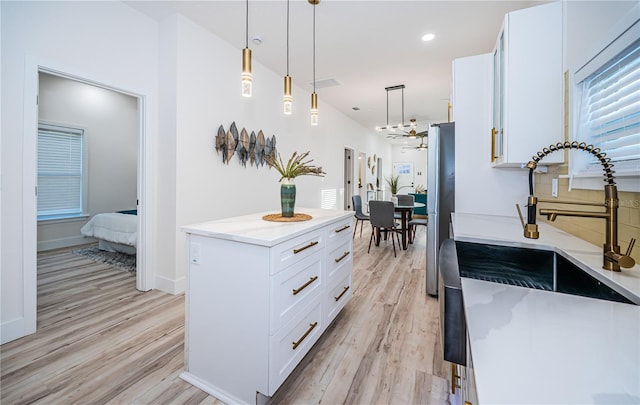 kitchen with light hardwood / wood-style flooring, light stone countertops, pendant lighting, white cabinets, and stainless steel refrigerator