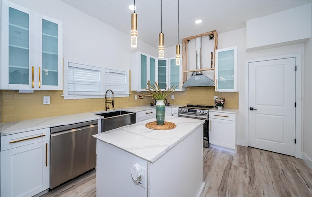 kitchen featuring a kitchen island, stainless steel appliances, light stone countertops, pendant lighting, and white cabinets