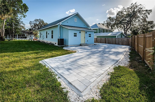 rear view of house with central air condition unit, a patio area, and a lawn