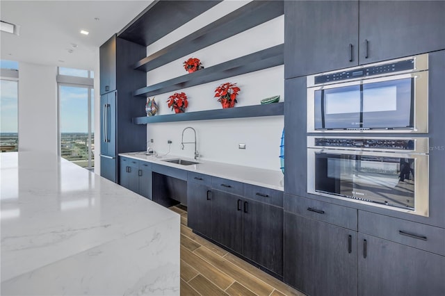 777 3rd Ave N Unit 1203, Saint Petersburg, FL 33701 - kitchen featuring a sink, open shelves, wood finished floors, double oven, and light stone countertops