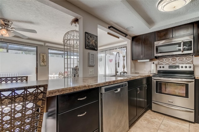 kitchen featuring appliances with stainless steel finishes, a textured ceiling, dark brown cabinets, and sink