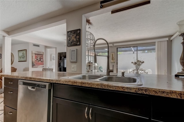 kitchen with a textured ceiling, stainless steel dishwasher, and sink