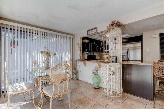 dining area featuring sink, light tile patterned floors, and a textured ceiling