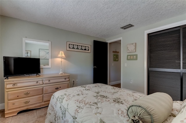 bedroom featuring light tile patterned flooring and a textured ceiling