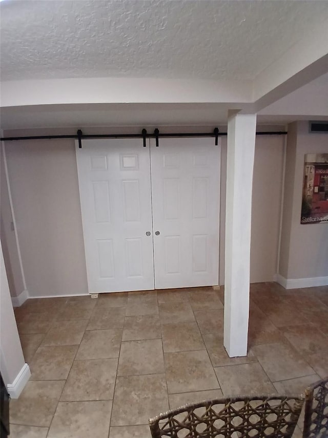 foyer entrance with a barn door, light tile patterned floors, and a textured ceiling