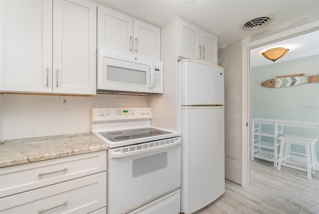 kitchen with light wood-type flooring, white cabinetry, light stone counters, white appliances, and tasteful backsplash