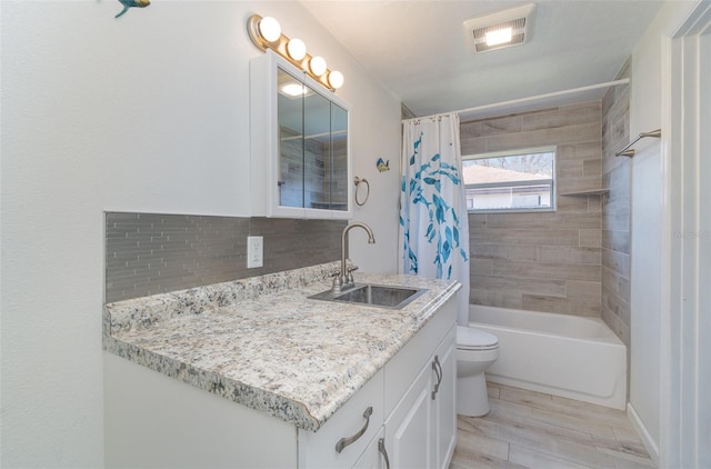 full bathroom with decorative backsplash, hardwood / wood-style flooring, toilet, vanity, and shower / bathtub combination with curtain