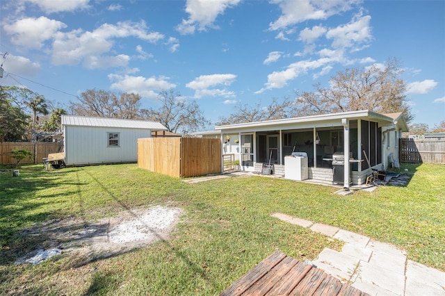 rear view of property with a yard, a sunroom, and a shed