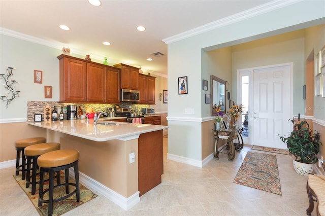 kitchen with kitchen peninsula, tasteful backsplash, appliances with stainless steel finishes, a kitchen bar, and sink