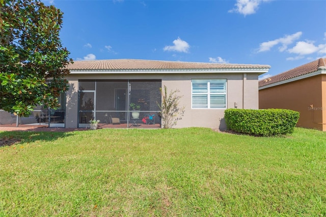 rear view of property with a lawn and a sunroom