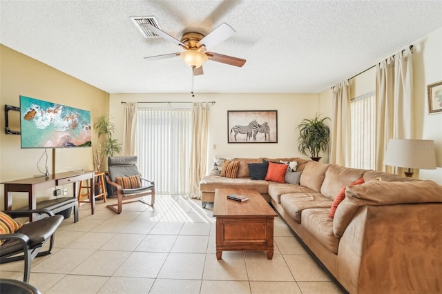 living room with a textured ceiling, light tile patterned floors, and ceiling fan