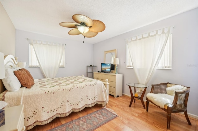 bedroom with light wood-type flooring, multiple windows, and ceiling fan