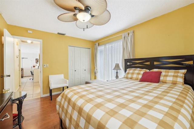 bedroom with ceiling fan, a textured ceiling, a closet, and light hardwood / wood-style flooring