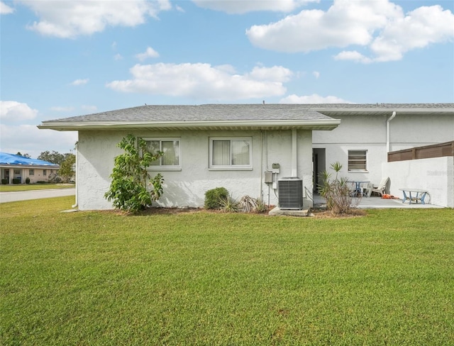 back of property with a lawn, central AC, and a patio