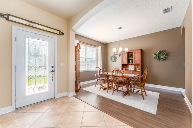 dining space featuring light hardwood / wood-style flooring, a textured ceiling, and a chandelier