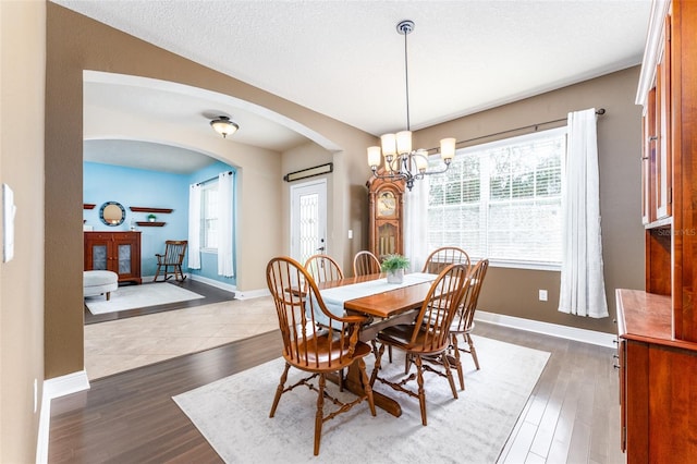 dining room featuring a textured ceiling, dark hardwood / wood-style flooring, and a notable chandelier