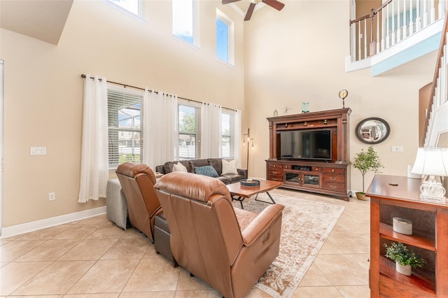 living room featuring light tile patterned floors, ceiling fan, and a towering ceiling